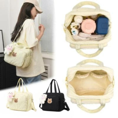 Sac a langer en deux coloris, avec une vue montrant l’intérieur rempli d’essentiels pour bébé, porté à l’épaule par une femme.