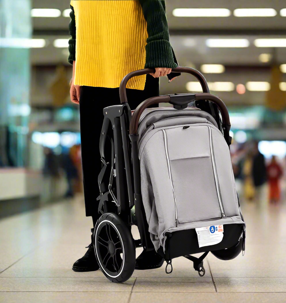 Maman tient une poussette compacte pliée