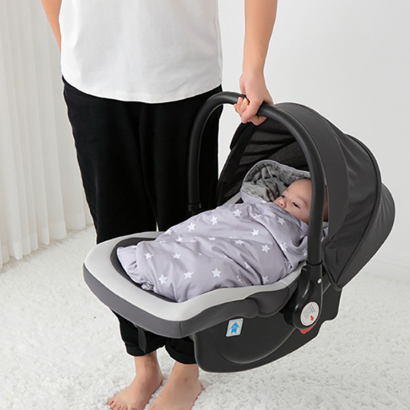 Bébé dans nid d’ange gris étoilé installé dans siège auto porté par maman