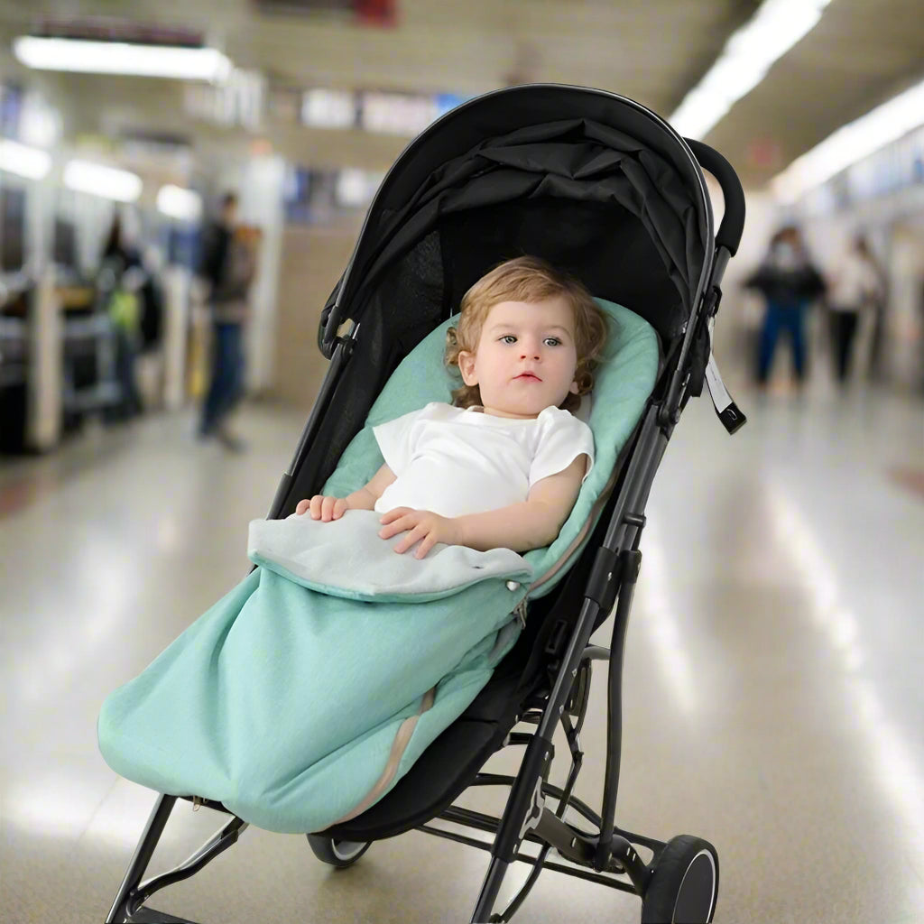 Bébé installé dans nid d’ange motif petit dinosaure dans poussette