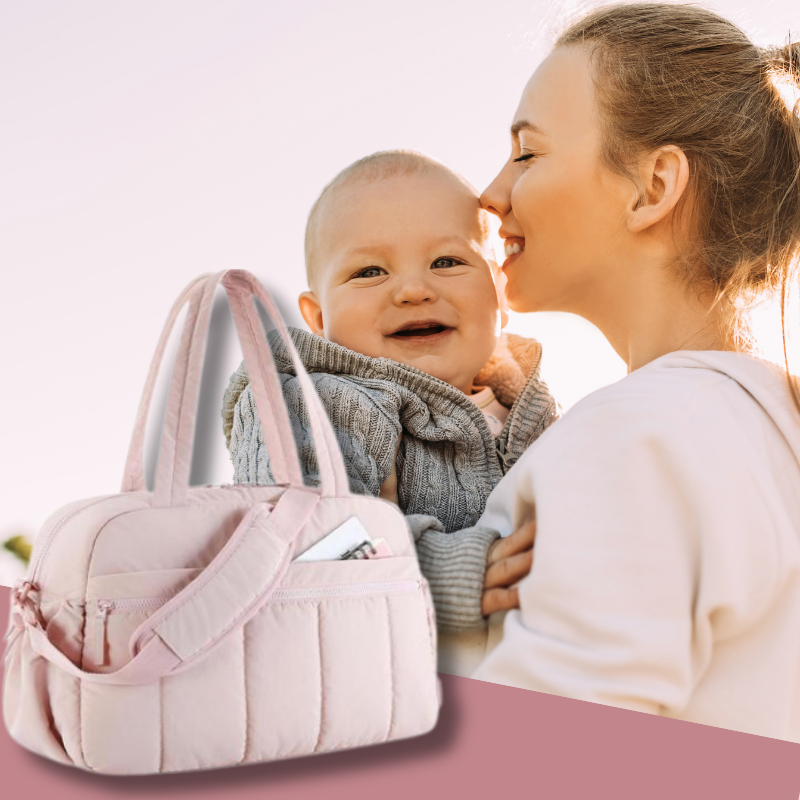 sac a langer bebe rose et maman tenant son bébé, tous deux éclairés par le soleil