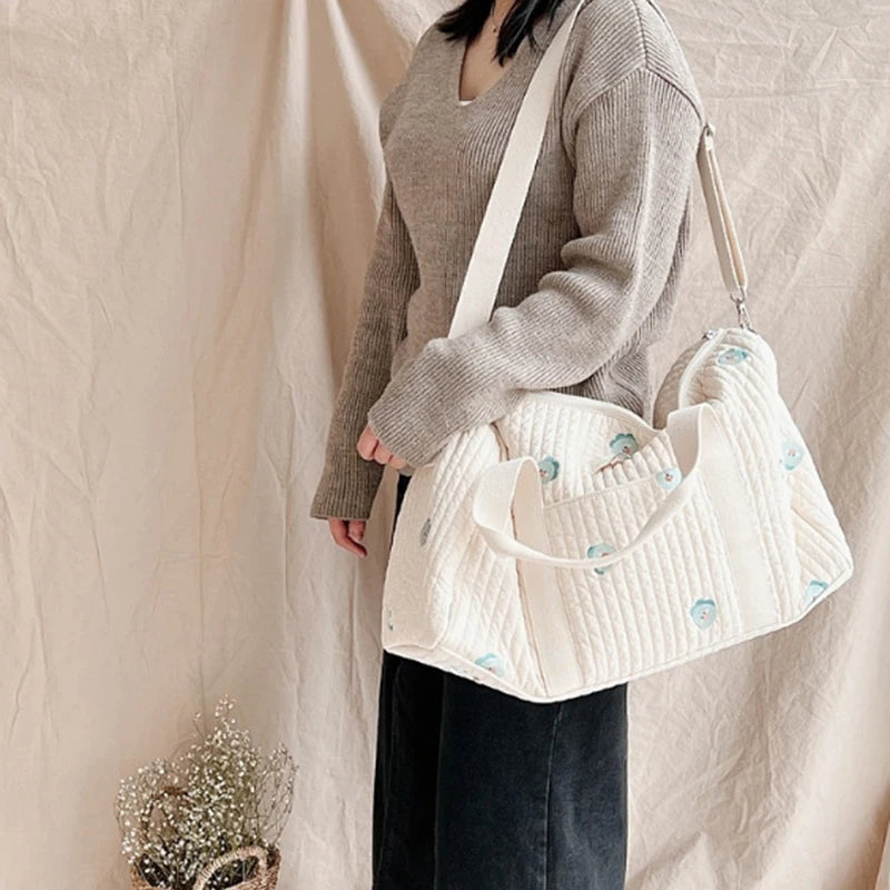 Maman portant un sac à langer sur l’épaule, vue de profil, avec un pot de fleurs en bas à gauche
