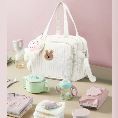 sac a langer jaune motif lapin, entouré de tous les essentiels du bébé, posé sur une table