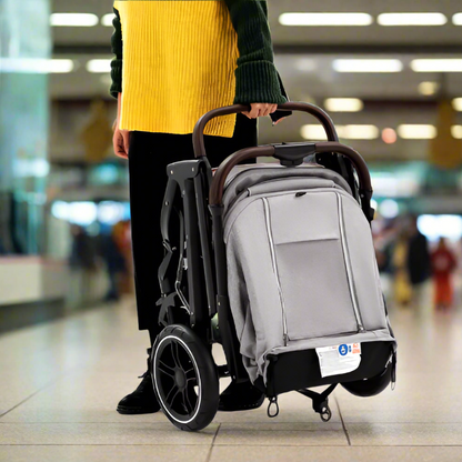 Maman tient une poussette compacte pliée