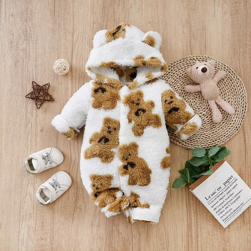 Nid d’ange bebe imprimé petit ours, posé sur une table avec une petite chaussure, un ours en peluche et d’autres accessoires décoratifs