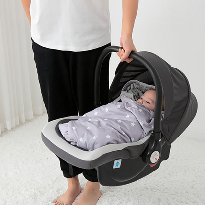 Bébé dans nid d’ange gris étoilé installé dans siège auto porté par maman