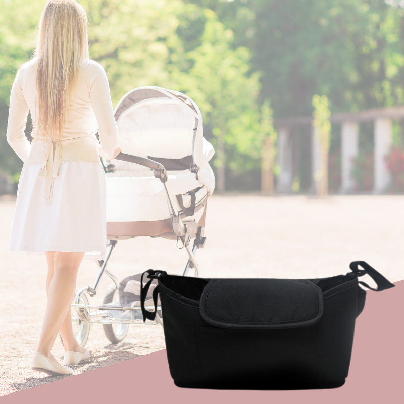 Maman poussant une poussette dans un parc avec un sac a langer bebe noir